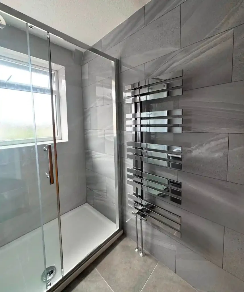 Tiled bathroom and walk-in shower installtion wth chrome wall-radiator