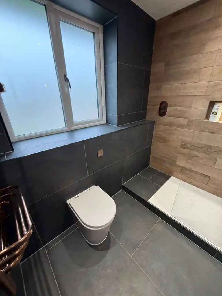 WC fitted flush to wall and grey tiles with contrasting wood effect for shower cublice area